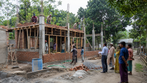 গ্রামীণ এলাকায় নির্মাণাধীন একটি সামাজিক অবকাঠামো পরিদর্শন করছেন স্থানীয় বাসিন্দা ও প্রকৌশলী